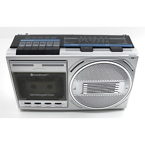 Boombox argenté sur fond blanc, avec un lecteur de cassettes et un haut-parleur.