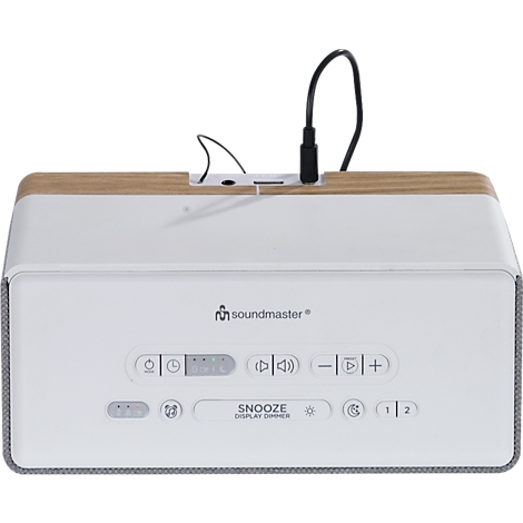 Radio soundmaster blanc avec dessus aspect bois. Panneau de commande avec boutons et texte en dessous. Un câble USB est connecté.