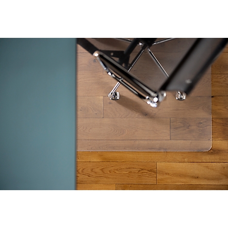 Vue de dessus d'une chaise de bureau à roulettes sur un tapis de sol transparent, posé sur un plancher en bois.