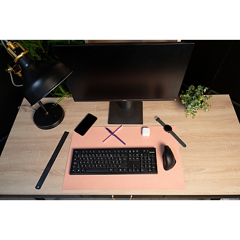 Bureau avec moniteur, clavier, souris, montre, écouteurs et téléphone portable. Des stylos sont placés sur un tapis de souris rose.