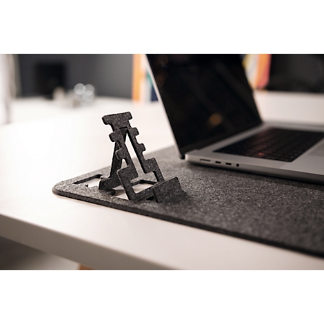 Un support d'ordinateur portable en feutre gris est posé à côté d'un ordinateur portable sur un tapis en feutre gris. L'ordinateur portable est ouvert.