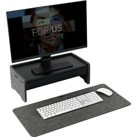 Un écran d'ordinateur affichant le texte "FOR US" est sur une rehausse noire. En dessous : clavier, souris et un tapis en feutre gris.