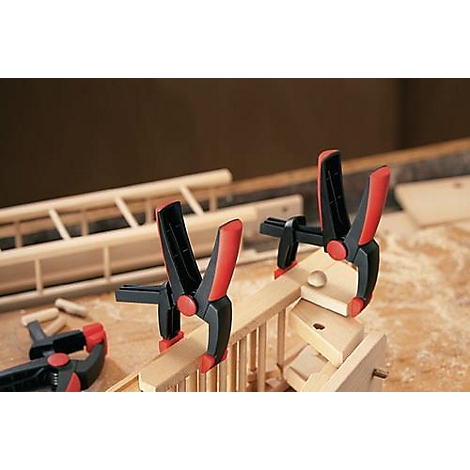 Wooden construction, secured with black and red clamps, close-up shot.