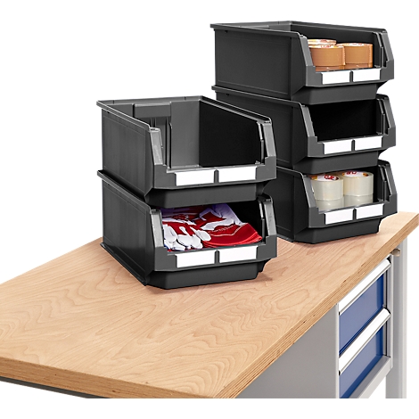 Des bacs en plastique gris, remplis de matériaux, reposent sur un établi.