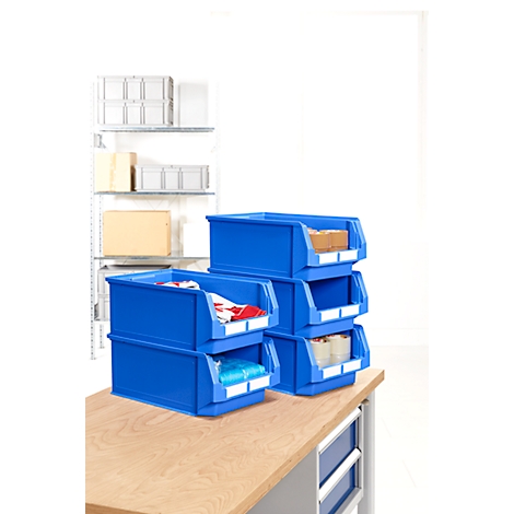 Blue plastic boxes, filled with various materials, on a wooden table. Background shelf with more boxes.