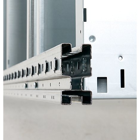 Close-up of a metal profile with perforations and hooks inserted into another metal part.