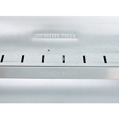 Close-up of a silver metal part with cutouts and lettering. Top: "ZB 951815 150 kg"; Bottom: "KOCH & SCHÄFER"