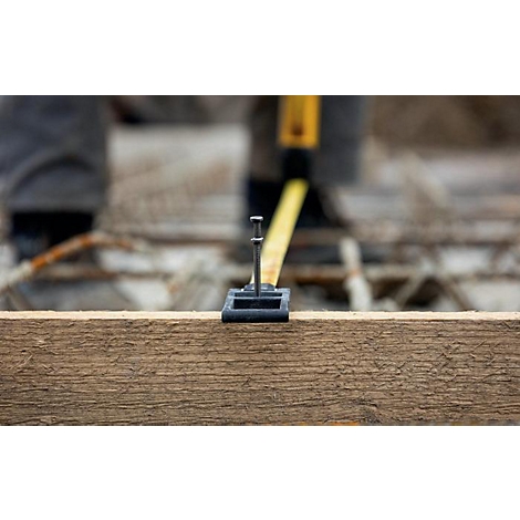 Een spijker bevestigd aan een houten plank. Meten op de achtergrond.