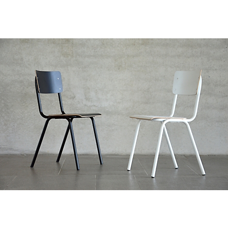 Two chairs, one black, one white, stand side by side in front of a textured wall.