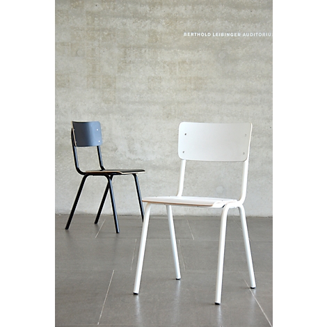 Two chairs in front of a concrete wall. One is black, the other white. The name "BERTHOLD LEIBINGER AUDITORIUM" can be seen in the background.