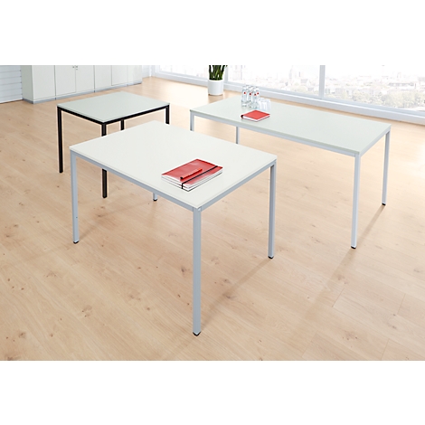 Drei Tische mit unterschiedlichen Formen. Auf dem mittigen Tisch liegt ein rotes Notizbuch. Holzfußboden.