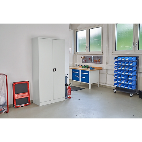 Werkstatt mit Werkbank, Schrank, Regalen und Notausrüstung. Fenster im Hintergrund.