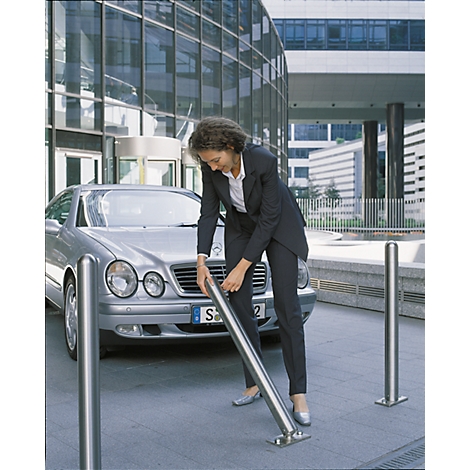 Business woman in suit installing a stainless steel bollard. A silver car is next to her.