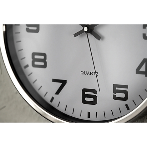 Close-up of a clock with a white face and black hour markers. The word "QUARTZ" is visible in the center.