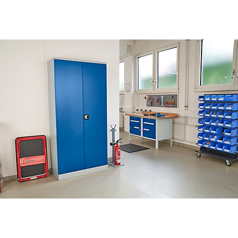 Werkplaatsinterieur: Blauwe kast, werkbank, rek met blauwe dozen en brandblusser.