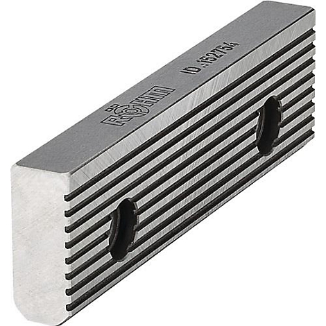 Een metalen blok met groeven en twee gaten. Opschrift is gegraveerd op de bovenkant.