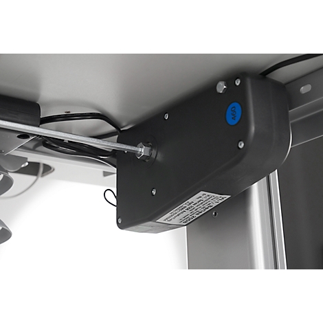 Gray motor under a table top, with cables, screws and a blue sticker.