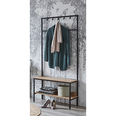 Schwarzer Kleiderständer mit grüner Strickjacke, hellem Schal und Bank. Darauf Schuhe, Zeitschriften, Dose.