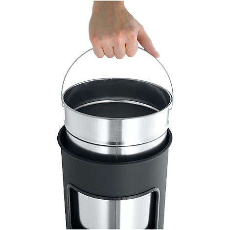 Hand holding a metal container with handle. The container is in a black plastic housing.