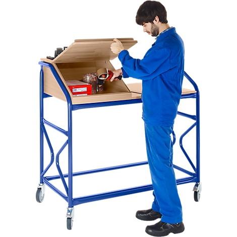 Man in blue work clothes opens the flap of a packing table with wheels. Packing materials are on the table.