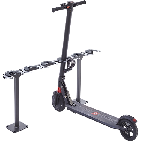 A black electric scooter stands on a stand. The handlebars are at the top, the wheels at the bottom. A holding system for several scooters is next to it.