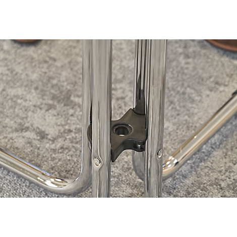 Close-up of a chair. Chrome legs connected by a black plastic element, on gray carpet.