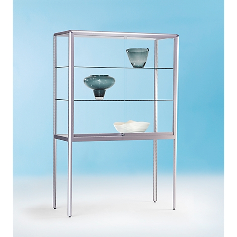 Ein modernes Glasvitrinen-Regal mit drei Regalen, auf dem zwei dekorative Vasen und eine Schale platziert sind, vor einem blauen Hintergrund.