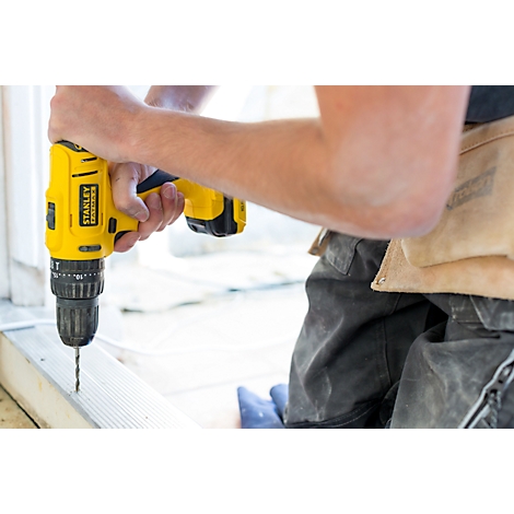Person drills into wood with a yellow cordless drill. Tool brand: Stanley.