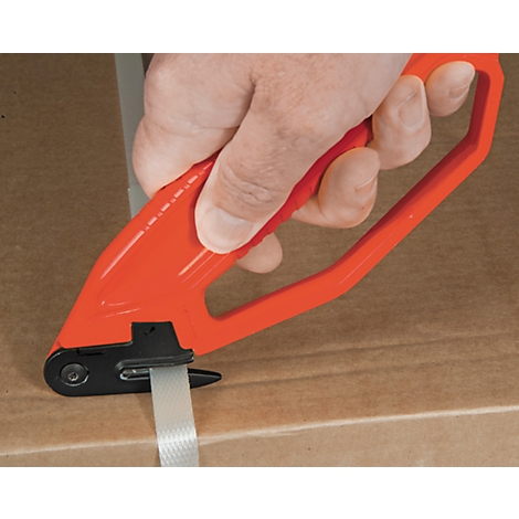 A hand holds a red strapping tool, tensioning a white strap on a cardboard box.