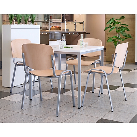 Een tafel met vier stoelen in een eethoek. Licht houten zittingen, zilveren frames. Tegelvloer.