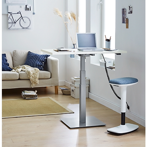 A bright workspace with a height-adjustable desk, chair, laptop, and sofa in the background.