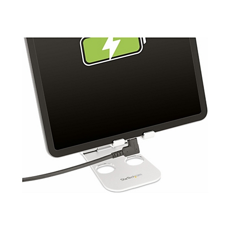 Ein Tablet mit Ladesymbol auf einem Ständer, Kabel verbunden.