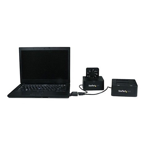 Un ordinateur portable noir connecté à deux stations d'accueil pour disque dur noires avec le logo StarTech.com. Le tout sur fond blanc.