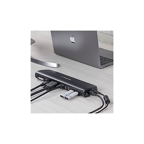 Hub USB-C noir avec divers ports, deux clés USB, un ordinateur portable sur une table en bois clair.