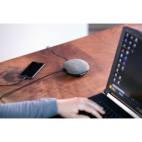 Appareil gris en forme de pierre avec câbles, connecté à un téléphone et un ordinateur portable. Personne utilisant l'ordinateur portable.