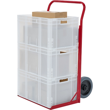 Een rode steekwagen met drie transparante plastic dozen. Bovenop ligt een bruine kartonnen doos.