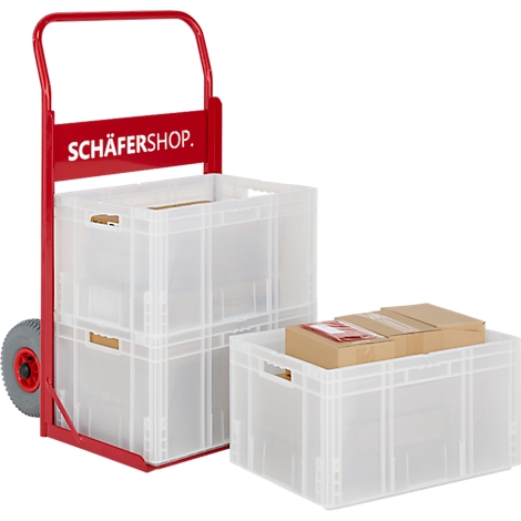 Rode steekwagen met twee transparante plastic dozen. Een andere doos, gevuld met kartonnen dozen, staat ernaast.