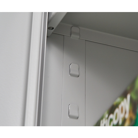 Grey metal structure with square protrusions and the corner of a sheet with text.