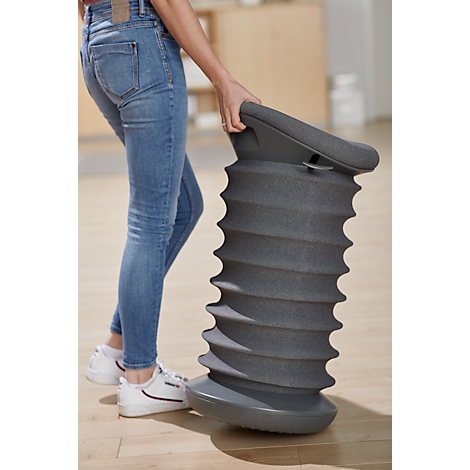Person holding a gray, spiral-shaped stool. The person is wearing blue jeans and white shoes.