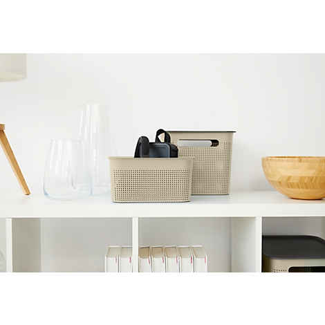 Two beige storage baskets with handles sit on a white shelf. Next to them are glass vases and a wooden bowl.