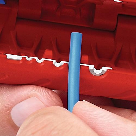 Close-up van een rode draadstripper met een blauwe kabel. De tang wordt vastgehouden door een hand.