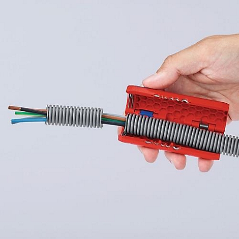 Hand die een rood gereedschap vasthoudt dat een grijze kabelgoot opent met gekleurde kabels die erdoorheen lopen.