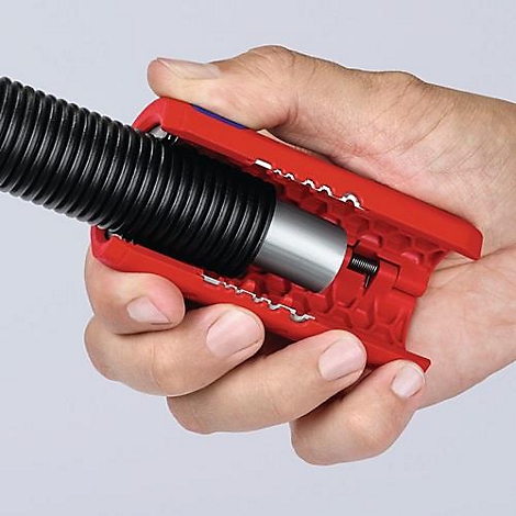 A hand holds a red tool clamping a black, corrugated hose.