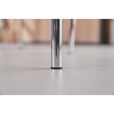 Close-up of two chrome chair legs standing on a light floor. The legs have black plastic feet.