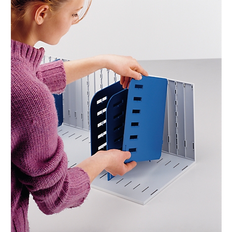 A woman inserts a blue divider into a gray filing system.