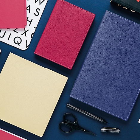 Vue de dessus de stylos, ciseaux et carnets de différentes couleurs sur fond bleu.