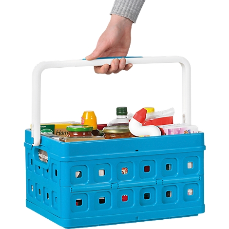A hand holding a blue, filled shopping basket with a white handle. The basket contains various groceries.