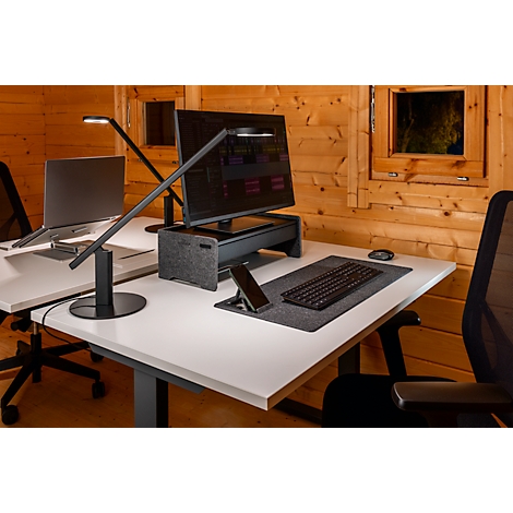 Configuration de bureau avec bureau, moniteur, ordinateur portable et lampe de bureau. L'arrière-plan est un mur en bois avec une fenêtre.