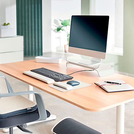 Un bureau moderne avec ordinateur, clavier, souris et bloc-notes. Une chaise est également visible.