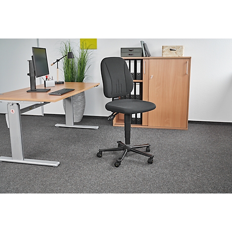 Office chair in an office, in front of a desk, cabinet and gray carpeted floor. Black chair with wheels, adjustable height, and padded seat and backrest.